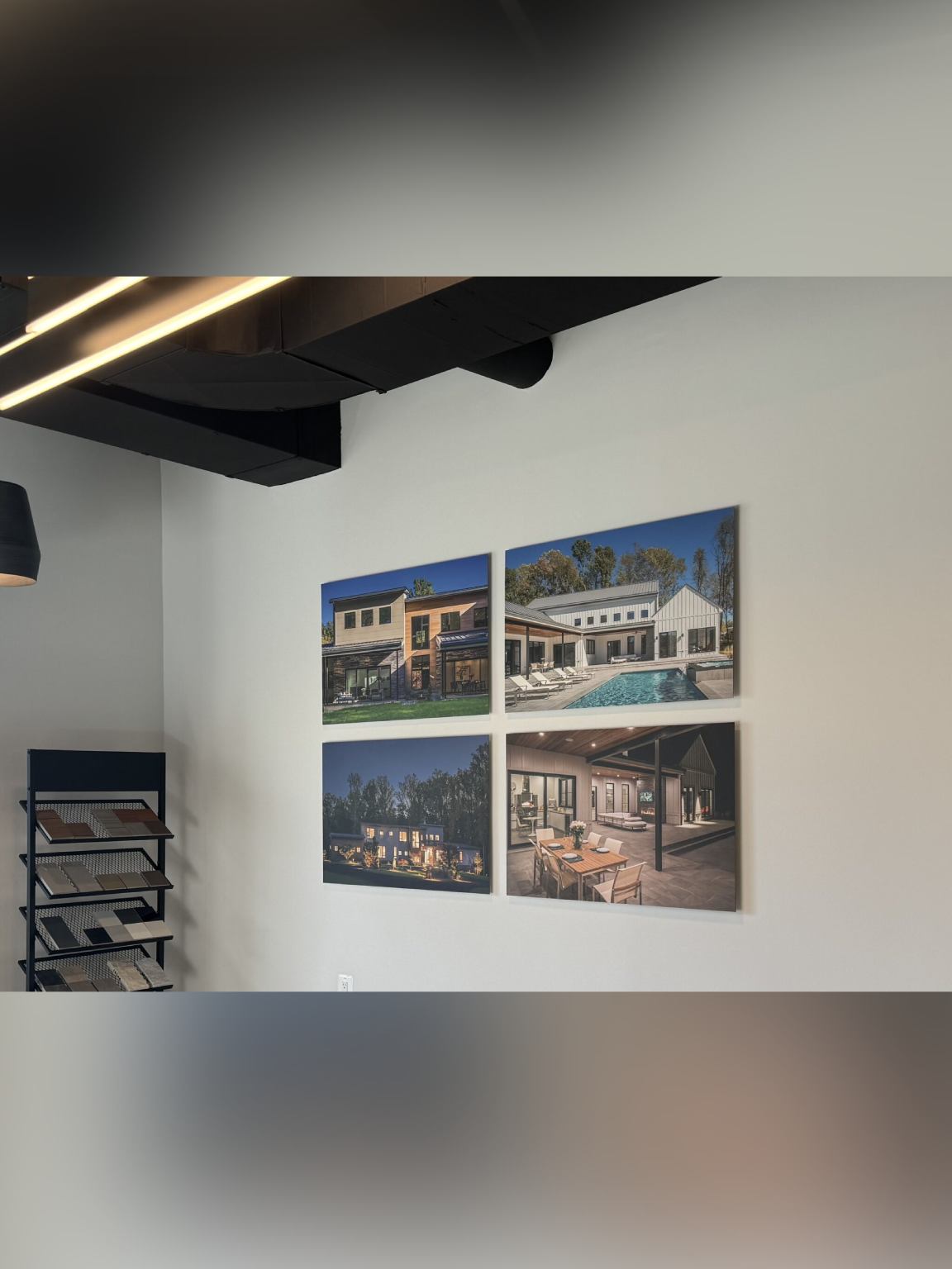 Four architectural photographs displayed on a white wall under black ceiling beams.