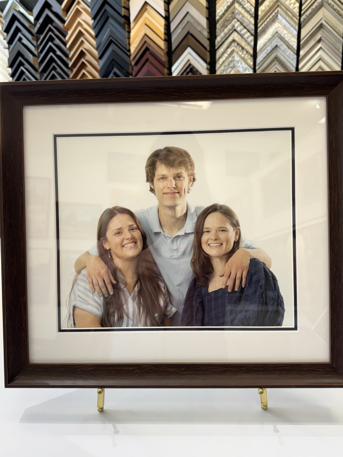 A framed photo of three smiling people posing together indoors.