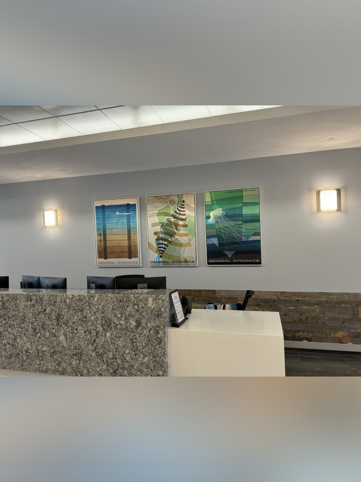 Modern office reception area with stone desk and wall art.