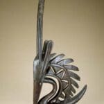 Intricate African wooden sculpture with elongated features.