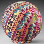 Colorful patchwork-patterned sphere on gray background.