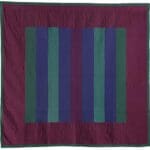 Colorful striped quilt with geometric design.