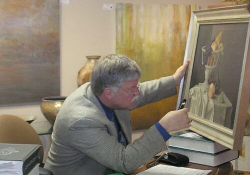 Man examining framed painting in gallery.