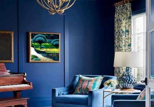 Blue living room with piano and armchairs.