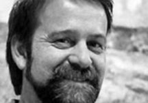 Smiling man with a beard outdoors.